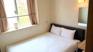 a bed sitting in a room with two windows at Hotel-澄Sumi-波の上ビーチ徒歩5分 in Naha