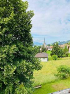 a view of a field with a church and a tree at Stilvolles Loft-Apartment in Gais