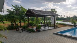 a pavilion with a picnic table and a swimming pool at Guesthouse AngaLampoe in Lelydorp +3 photos