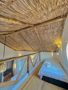 a bed in a room with a straw ceiling at Pousada em Paracuru Casa Eco Kite Surf & Relax in Paracuru