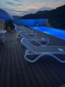 a row of lounge chairs on a deck next to a swimming pool at Santa Cruz Condo in Santa Cruz Huatulco