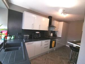 a kitchen with white cabinets and a black counter top at Superhost House Brechin sleeps 6, 3 bedrooms in Brechin