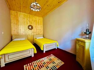 two beds in a room with yellow sheets at Beghela in Glola