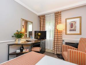 a hotel room with a desk with a television and a chair at Mercure Johannesburg Midrand in Midrand