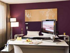 a computer monitor on a desk in a bedroom at Congress Hotel Mercure Nürnberg an der Messe in Nuremberg