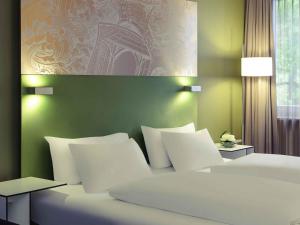 a bedroom with two white beds and a green wall at Congress Hotel Mercure Nürnberg an der Messe in Nuremberg