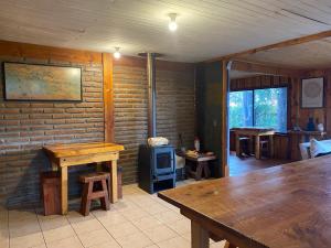 a room with a brick wall with a wooden table and a stove at Hostel Raíz Del Pillán in Pucón