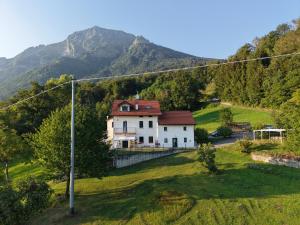a house on a hill with a mountain in the background at Fastuc B&B in Ponte nellʼAlpi