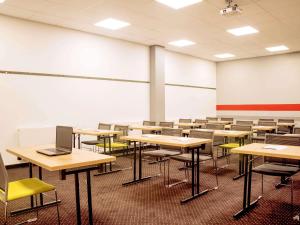 Ein leeres Klassenzimmer mit Tischen, Stühlen und einem Laptop in der Unterkunft Hotel Ibis Łódź Centrum in Łódź