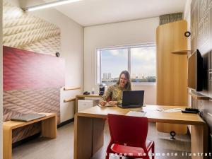 a woman sitting at a desk with a laptop at ibis Styles Curitiba Centro Civico in Curitiba