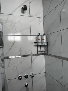 a bathroom with a shower with white marble walls at Alojamiento Pasaje Montes in Cruz del Eje