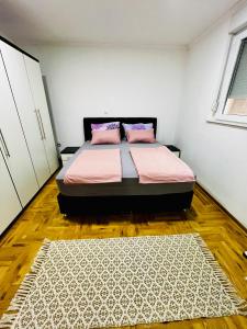 a bedroom with a bed with pink sheets and a rug at The Olive Tree Apartment in Ljubuški