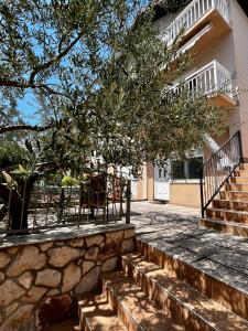a building with a tree and stairs in front of it at The Olive Tree Apartment in Ljubuški
