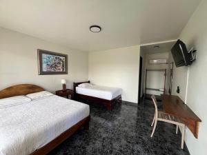a bedroom with two beds and a desk and a television at Brillasol Airport Hotel in Alajuela +42 photos