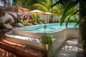 a swimming pool with stairs and chairs and umbrellas at El Corazón Boutique Hotel - Adults Only with Pool & Beach Club Access in Holbox Island +81 photos