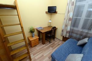 ペーチにあるCentrum Apartmanのデスク、ベッド、はしごが備わる小さな客室です。