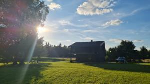 a barn in a field with the sun shining at Viešnagė gamtos prieglobstyje in Gūragiai