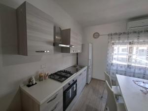 a kitchen with white cabinets and a stove top oven at Casa mariano in Marconia