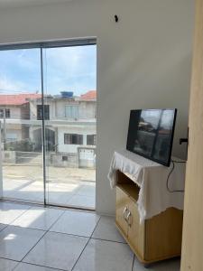 a television sitting on a dresser in a room with a window at Apartamento em Garopaba in Garopaba