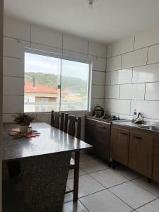 a kitchen with a table and a large window at Apartamento em Garopaba in Garopaba