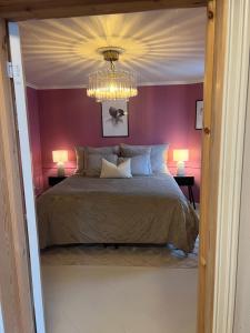 a bedroom with a bed with purple walls and a chandelier at The Old Bakery in Grimstad