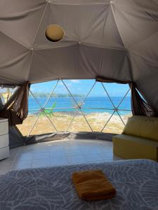 a bedroom with a bed and a view of the ocean at Dôme en face de la Passe de Tiputa in Rangiroa