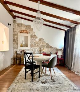 a dining room with a table and chairs and a stone wall at Garden in Šibenik