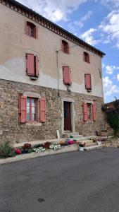 a stone building with red shuttered windows on it at Chez Phil et Marie in Pralong