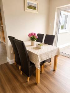 a table with black chairs and a vase of flowers on it at Hill House Westport in Mayo +1 photo