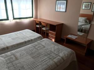 a room with two beds and a desk and a mirror at Hostal La Frontera in Ferrol