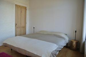 a bed in a white room with a wooden door at De Buur Van Beer in Ypres