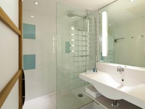 a bathroom with a sink and a glass shower at Novotel Leeds Centre in Leeds