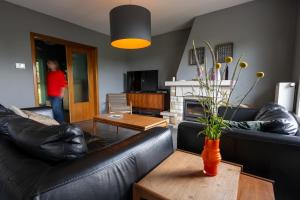 a living room with black leather furniture and a fireplace at Lumen nr5 in Bois