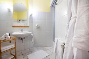 a white bathroom with a sink and a mirror at Hotel Das Gastein - ganzjährig inklusive Alpentherme Gastein & Sommersaison inklusive Gasteiner Bergbahnen in Bad Hofgastein +50 photos