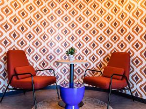 two chairs and a table in front of a wall at Hotel ibis Bragança in Bragança