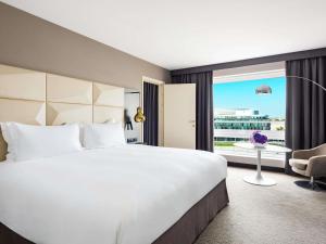 a hotel room with a large bed and a large window at Sofitel Warsaw Victoria in Warsaw