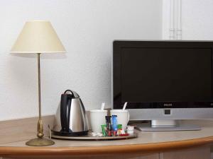 a desk with a computer monitor and a lamp at Mercure Nevers Pont De Loire in Nevers
