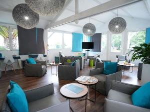 a living room with blue and gray furniture and windows at ibis Styles Quimper in Quimper