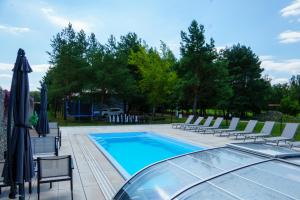 a swimming pool with chairs and umbrellas at Domki SHERWOOD in Gawłowo