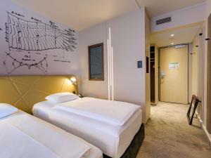 a hotel room with two beds and a drawing on the wall at Mercure Hotel Berlin City in Berlin