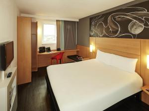 a hotel room with a large white bed and a desk at ibis Reading Centre in Reading