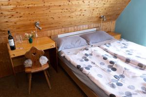 a bedroom with a bed and a desk with a bottle of wine at Horská chata LADA in Loučná pod Klínovcem