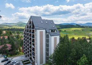 a building with a black roof on top of it at Apartman Tornik Relax&Spa 3 in Zlatibor