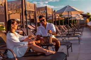 a man and woman sitting in chairs on a patio at Ilhabela Beach Residences in Ilhabela