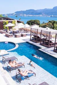 a group of people laying in the swimming pool at a resort at Ilhabela Beach Residences in Ilhabela