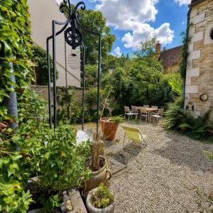 a garden with plants and a table and chairs at Le Jeu de Paume - Bail Partner in Mailly-le-Château