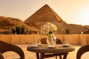a table with a vase of flowers and the pyramids at Crystal pyramid inn in Cairo