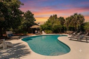 a swimming pool with chairs and a sunset in the background at Blue Mountain View - Private Pool in Santa Rosa Beach