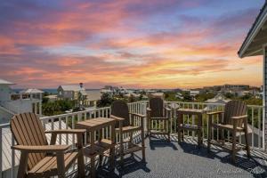 a group of chairs sitting on a balcony with a sunset at Blue Mountain View - Private Pool in Santa Rosa Beach