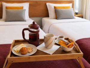 a tray with a tea kettle and food on a bed at Fervença Apartments in Vila Nova de Gaia
